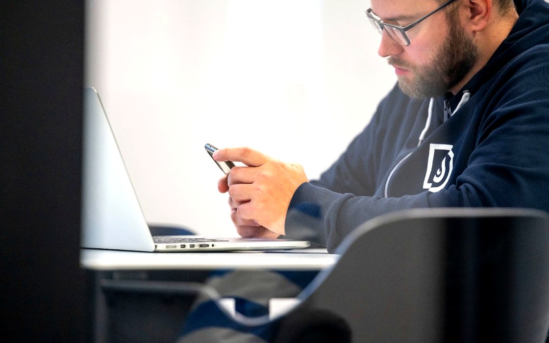Skupiony programista Droptica pracujący z laptopem i telefonem